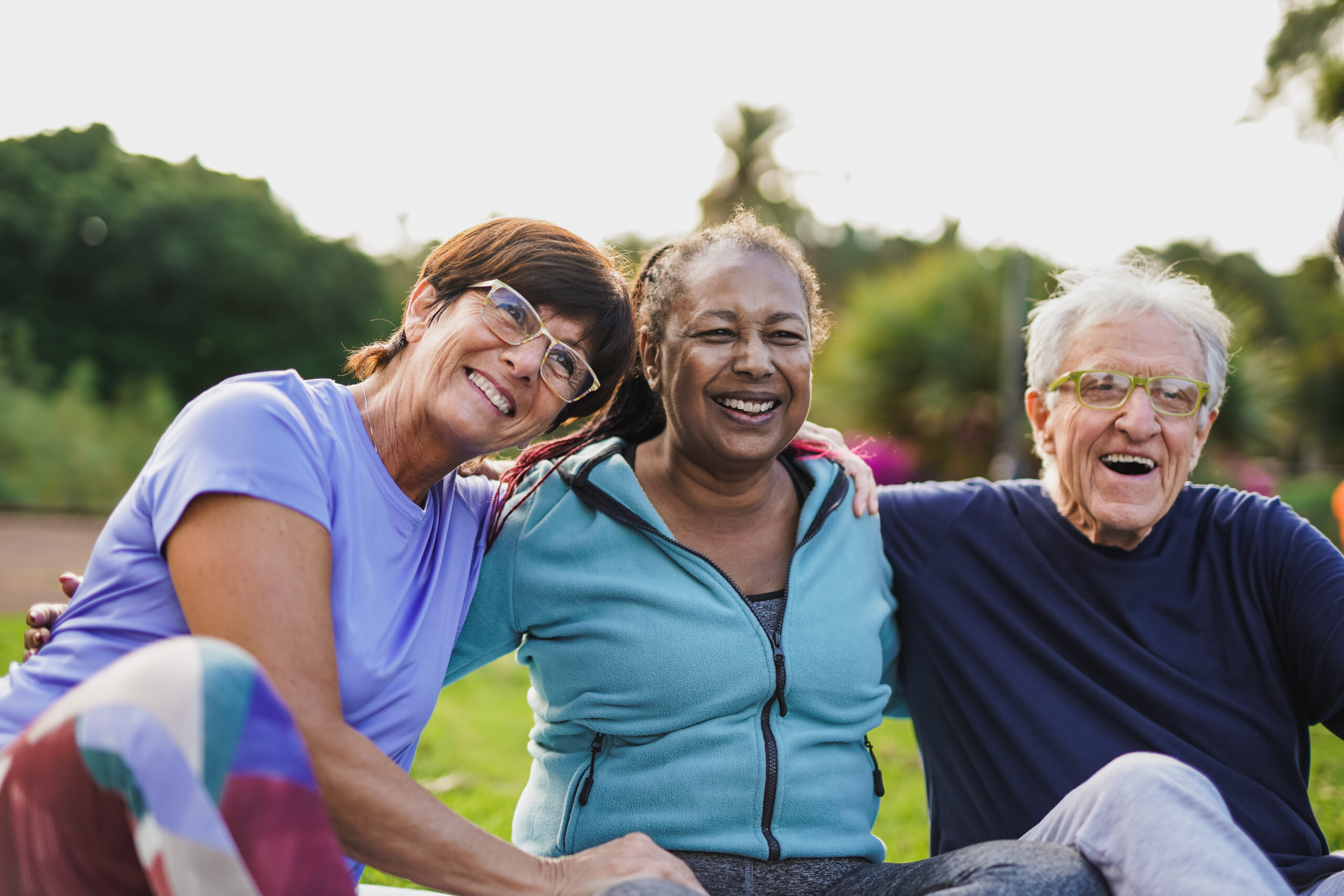 Happy elderly people having fun hugging each other outdoor after yoga lesson